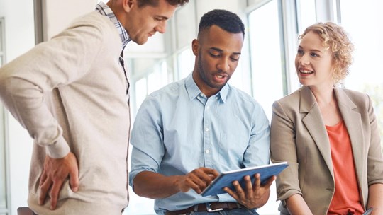 colleagues talking, looking at the tablet