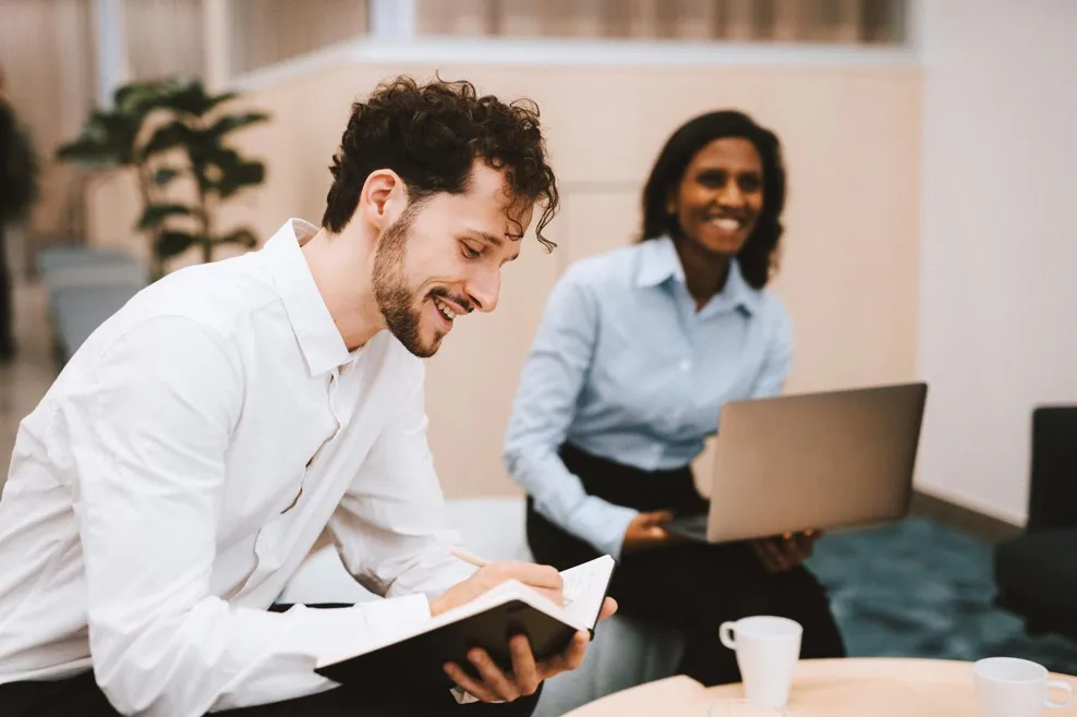 two people sitting in a meeting and smiling