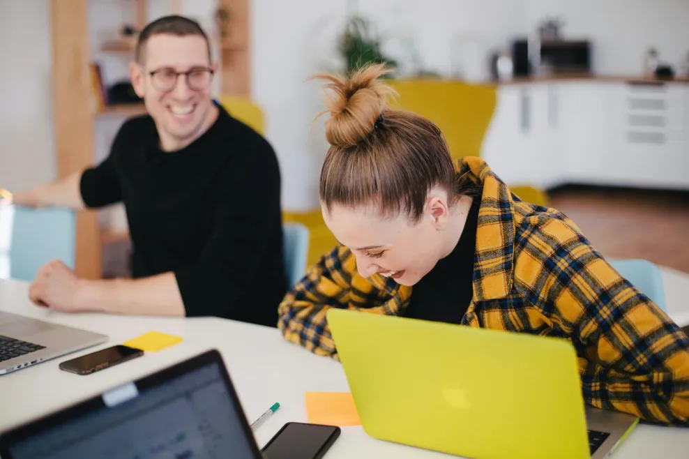 People laughing working on laptop in office