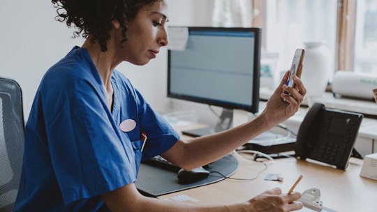 Doctor using a phone, giving patient an online consultation